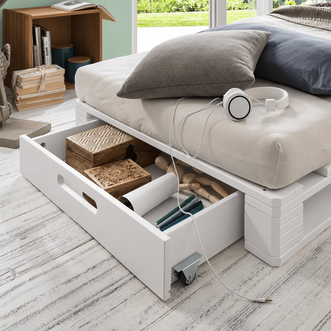 Opberglade op wieltjes aan voeteneinde van wit houten palletbed 90x200
